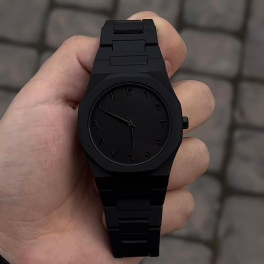 Reloj Catera negro mate sostenido en la mano, brazalete de eslabones negro